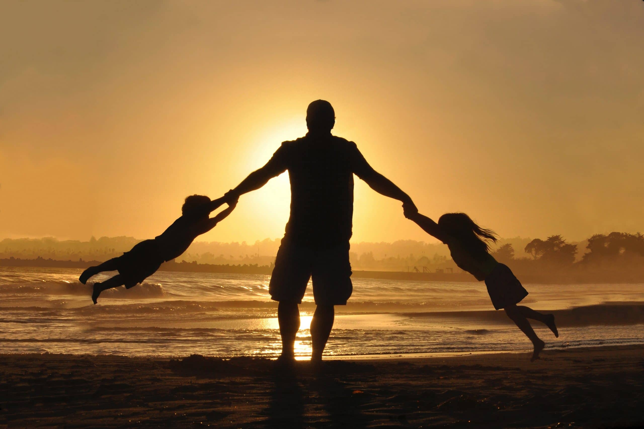 work-life balance - Dad swinging kids on a beach with sunset behind - Avoid being a Deadbeat Dad